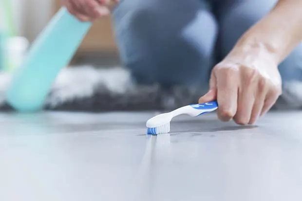 Fliesenfugen reinigen mit Zahnbürste.