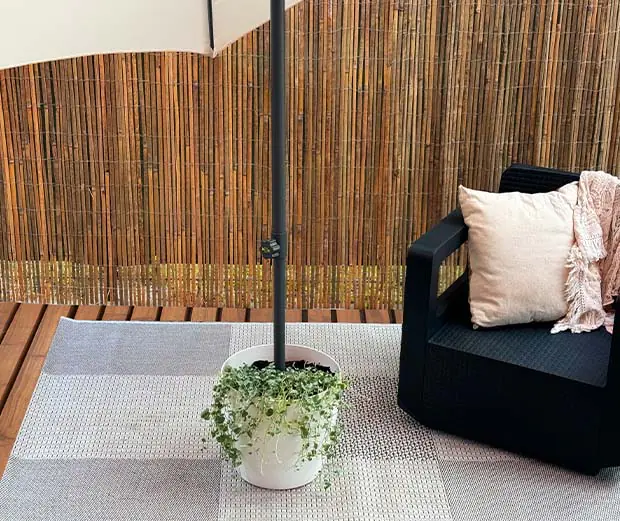 Der Schirmständer aus Pflanzen hält einen Sonnenschirm.