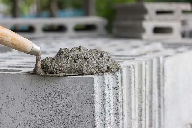 Eine Kelle mit frisch gemischtem Beton liegt auf einem Stein.