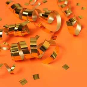 goldene Luftschlangen und Konfetti auf einer orangenen Tischdecke