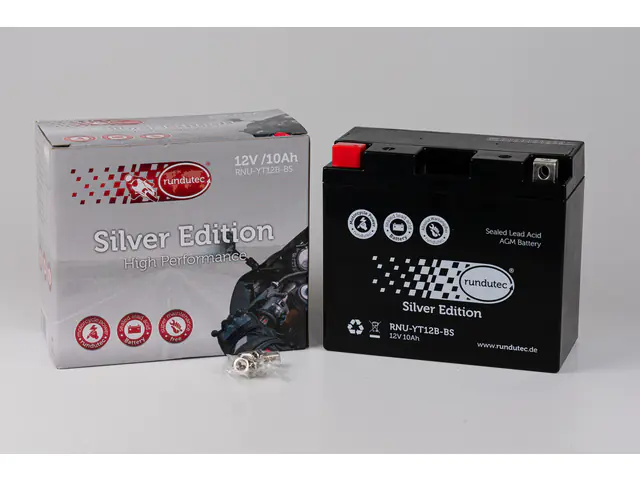 Schwarze AGM-Batterie der Marke rundutec, Modell Silver Edition, mit passender Produktverpackung in Silberoptik und Zubehörteilen auf weißem Hintergrund.