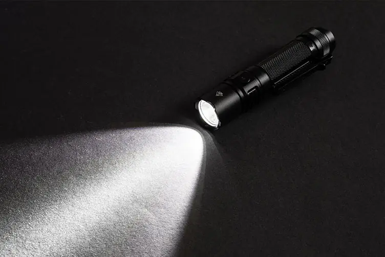 Schwarze, eingeschaltete Taschenlampe mit hellem Lichtstrahl auf dunklem Hintergrund.