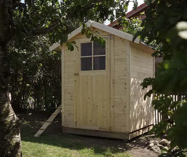 Selbstgebautes Hühnerhaus aus einem Gartenhaus, umgeben von Bäumen im Garten