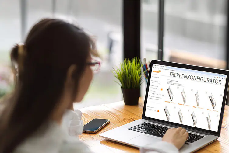 Person nutzt den „TREPPENKONFIGURATOR“ auf einem Laptop zur Planung verschiedener Treppenmodelle am Schreibtisch.