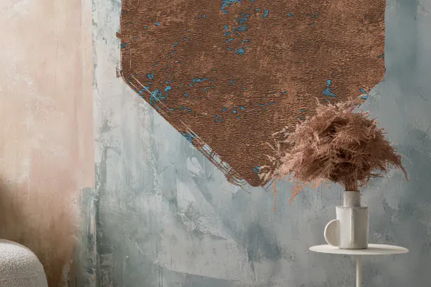 Vor einer kreativ gestalteten Wand in Cremefarbe und Betonoptik, davor steht eine Vase.