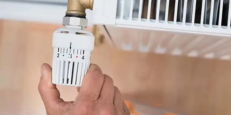 Eine Hand dreht am Heizkörperthermostat